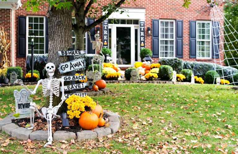 A colonial brick house decorated with a skull and halloween decorations during the fall.